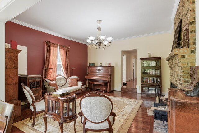 living area featuring crown molding, a brick fireplace, an inviting chandelier, and dark hardwood / wood-style flooring