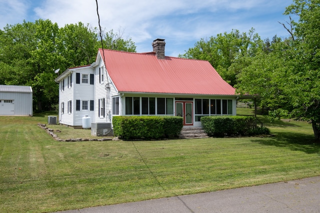 view of front facade with a front yard, a storage unit, and central AC unit