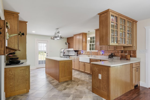 kitchen featuring a kitchen island, sink, a notable chandelier, decorative light fixtures, and tasteful backsplash