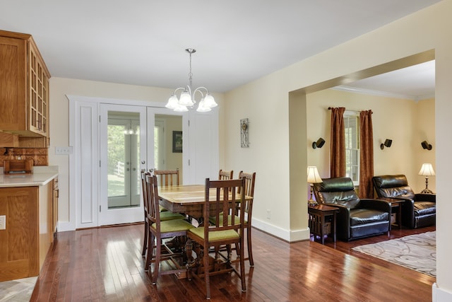 dining space with ornamental molding, a notable chandelier, and dark hardwood / wood-style flooring