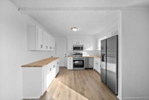 kitchen with light hardwood / wood-style floors, white cabinets, and stainless steel appliances