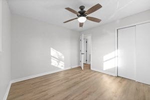 unfurnished bedroom featuring wood-type flooring, a closet, and ceiling fan