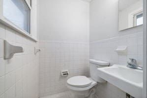 bathroom with toilet, tile walls, and sink