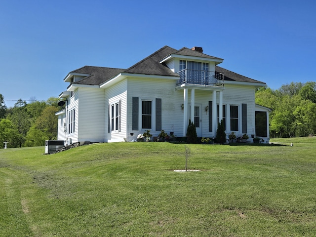 view of front of property featuring a balcony, a front yard, and central air condition unit