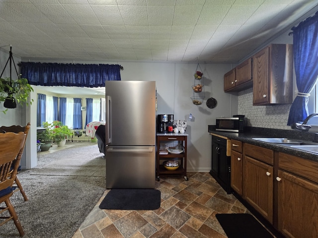 kitchen featuring dark carpet, sink, appliances with stainless steel finishes, and decorative backsplash