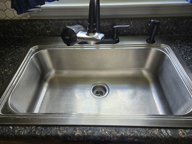 details featuring backsplash, sink, and dark stone counters