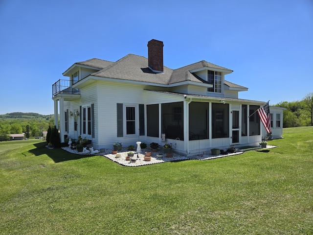 rear view of property with a balcony, a lawn, and a sunroom