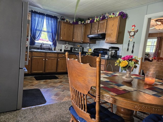 kitchen with a wealth of natural light, sink, decorative backsplash, and stainless steel refrigerator