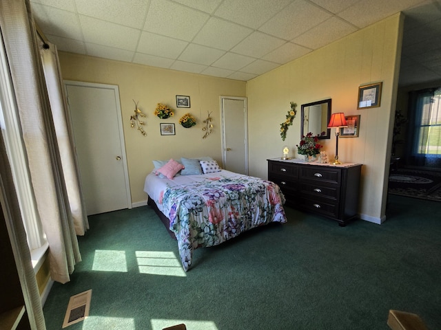 bedroom featuring dark carpet and a drop ceiling