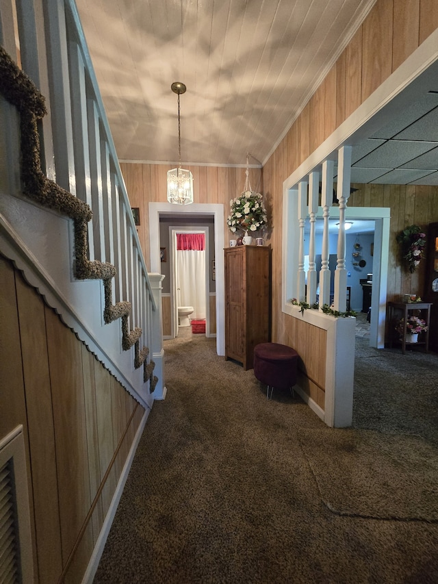 foyer featuring crown molding, carpet floors, and wooden walls