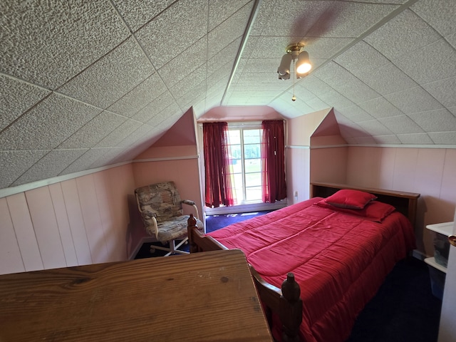 bedroom featuring wooden walls and vaulted ceiling