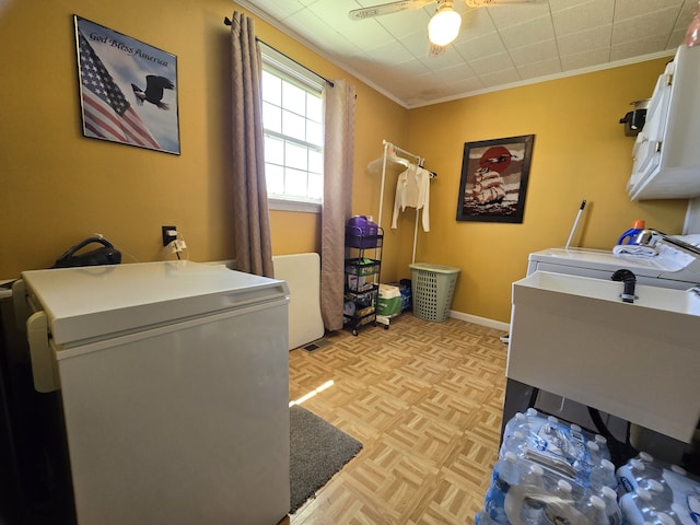 washroom featuring ornamental molding, washing machine and clothes dryer, light parquet flooring, and cabinets