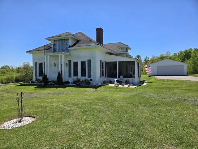 exterior space featuring a garage, a sunroom, a balcony, a front yard, and an outbuilding