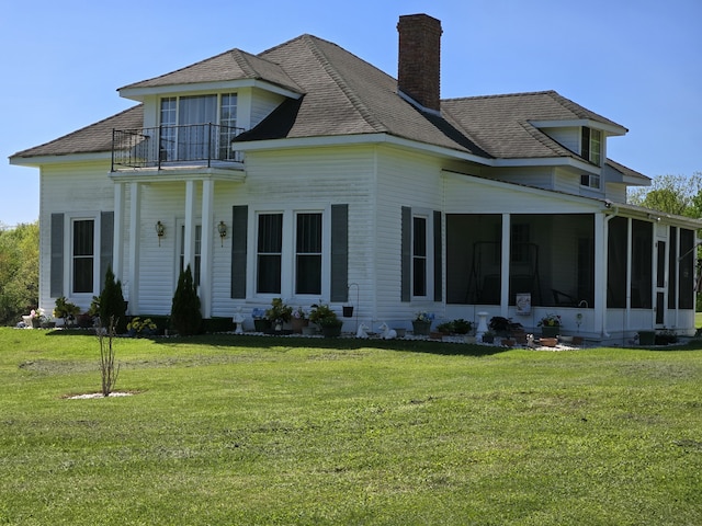 view of front of house featuring a sunroom, a front yard, and a balcony