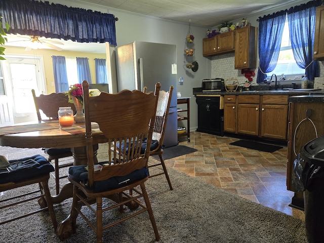 dining area with sink, crown molding, and ceiling fan