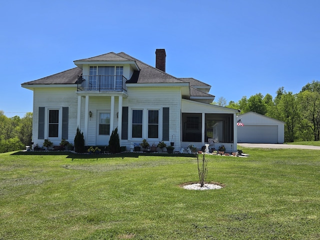 view of front facade featuring a balcony, a garage, a front lawn, and an outbuilding