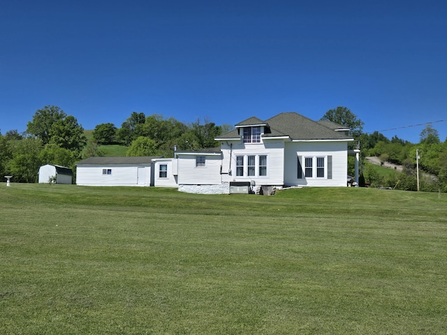 back of property featuring an outdoor structure and a lawn