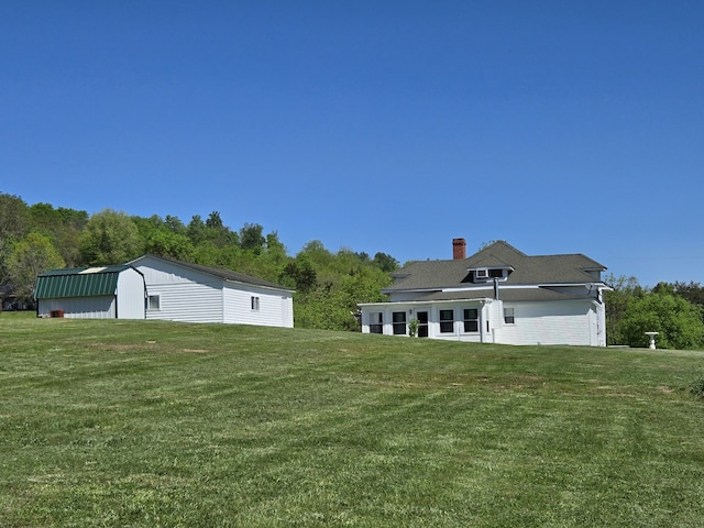 view of front of house with an outdoor structure and a front lawn