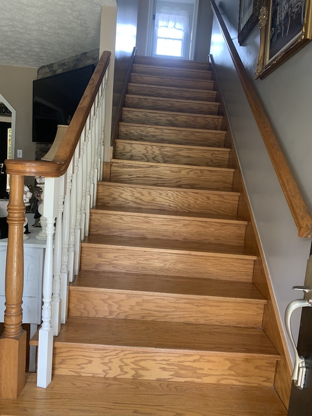 stairs with wood-type flooring and a textured ceiling