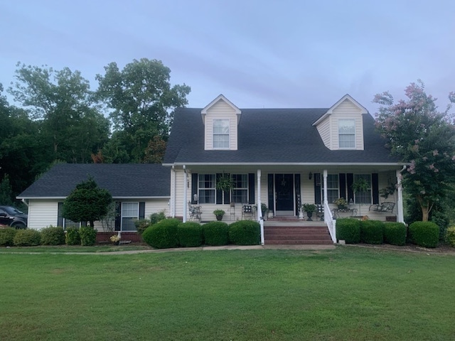 cape cod home with a front lawn and a porch