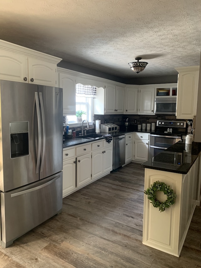 kitchen with white cabinetry, hardwood / wood-style flooring, appliances with stainless steel finishes, and sink