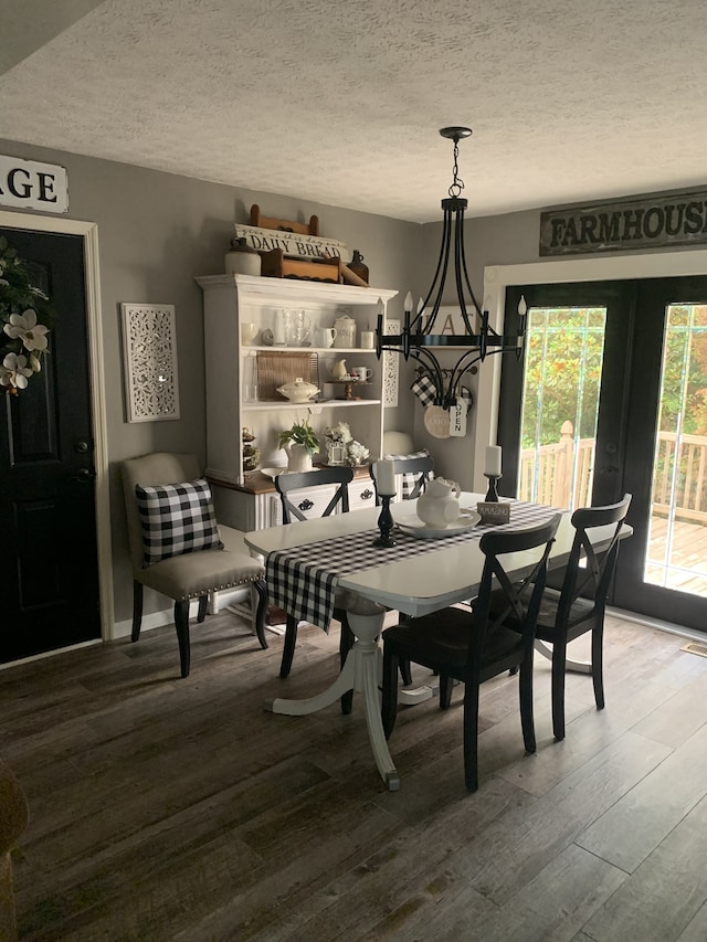 dining area with a textured ceiling, a notable chandelier, wood-type flooring, and french doors