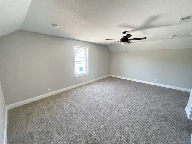 bonus room featuring dark colored carpet, lofted ceiling, a textured ceiling, and ceiling fan