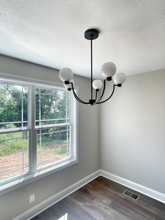 interior details with hardwood / wood-style floors, a textured ceiling, and a chandelier