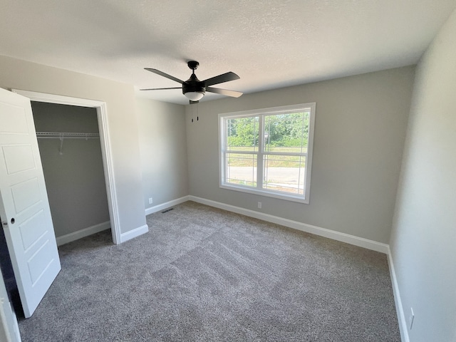 unfurnished bedroom featuring a closet, a textured ceiling, carpet, and ceiling fan