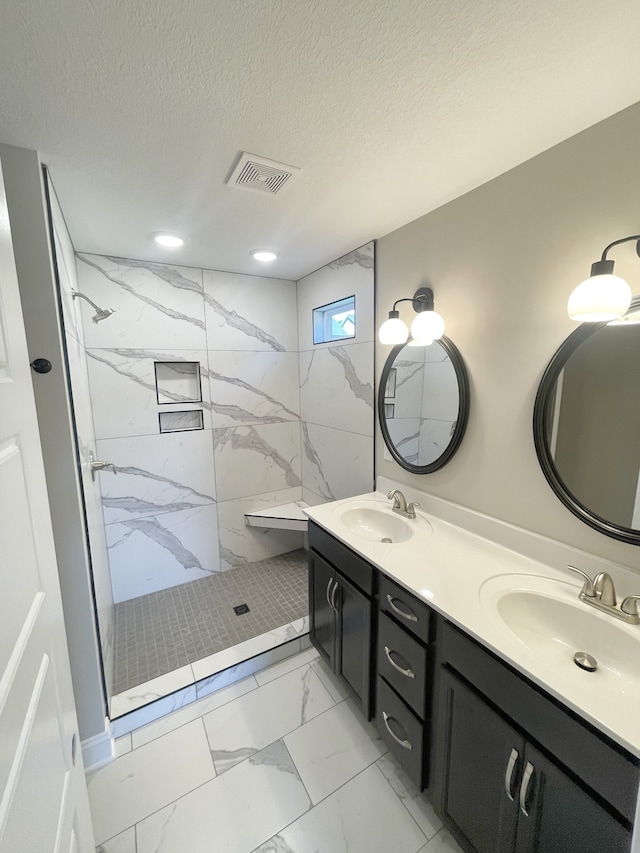 bathroom featuring a tile shower, a textured ceiling, and vanity