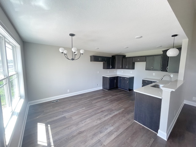 kitchen featuring sink, a notable chandelier, pendant lighting, a textured ceiling, and dark hardwood / wood-style flooring