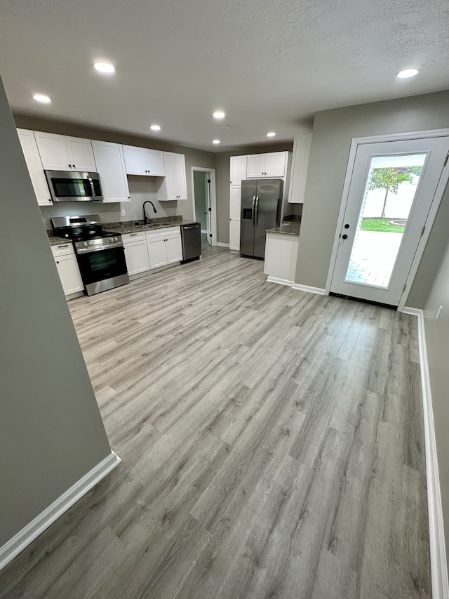 kitchen with white cabinets, sink, light hardwood / wood-style flooring, a textured ceiling, and appliances with stainless steel finishes