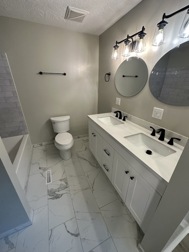 bathroom with vanity, toilet, and a textured ceiling