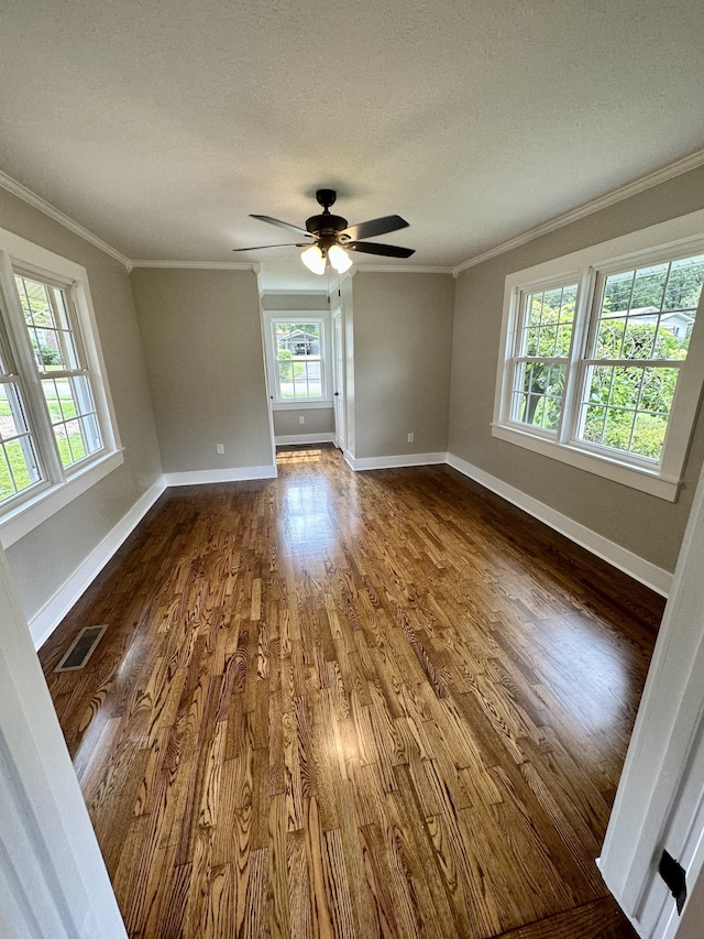 unfurnished room with crown molding, ceiling fan, dark wood-type flooring, and a textured ceiling