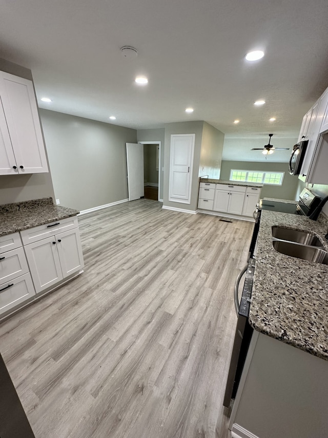 kitchen with stone counters, white cabinetry, sink, and light hardwood / wood-style floors