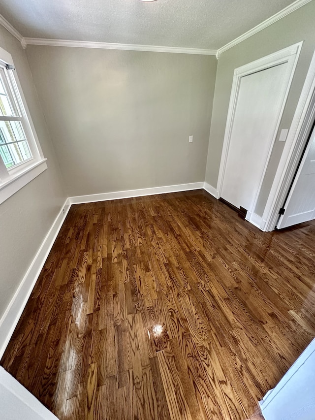 empty room featuring dark hardwood / wood-style flooring, ornamental molding, and a textured ceiling