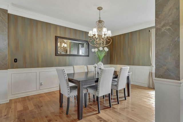 dining space featuring crown molding, an inviting chandelier, and light wood-type flooring