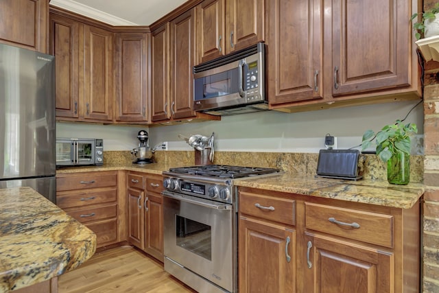 kitchen with light hardwood / wood-style floors, stainless steel appliances, and light stone counters