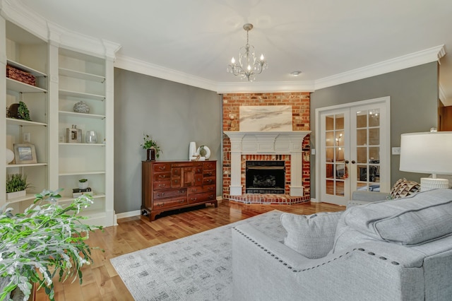 living room with light hardwood / wood-style floors, french doors, crown molding, and a brick fireplace