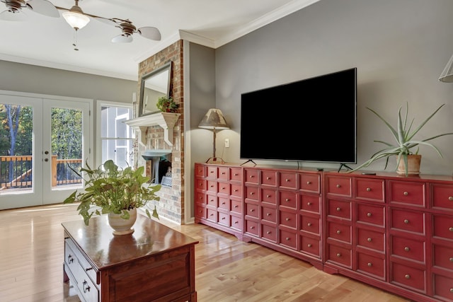 living room featuring french doors, ornamental molding, light wood-type flooring, a fireplace, and ceiling fan