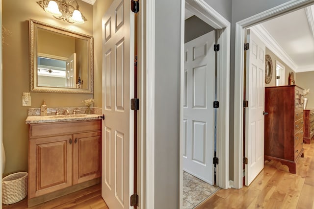 corridor with light hardwood / wood-style floors, ornamental molding, and sink