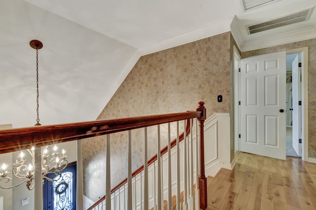 corridor featuring light hardwood / wood-style flooring, a notable chandelier, ornamental molding, and lofted ceiling