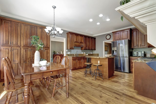 dining area featuring a chandelier, sink, crown molding, and light hardwood / wood-style floors