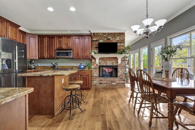 kitchen featuring black fridge, hanging light fixtures, light hardwood / wood-style floors, crown molding, and a chandelier