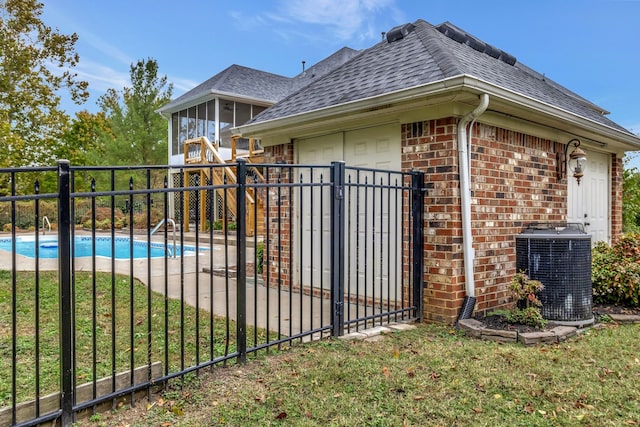 view of gate featuring central air condition unit, a fenced in pool, a yard, and a patio