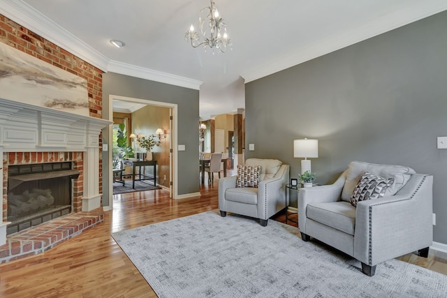 living room with an inviting chandelier, ornamental molding, light wood-type flooring, and a brick fireplace