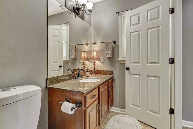 bathroom featuring toilet, a chandelier, and vanity