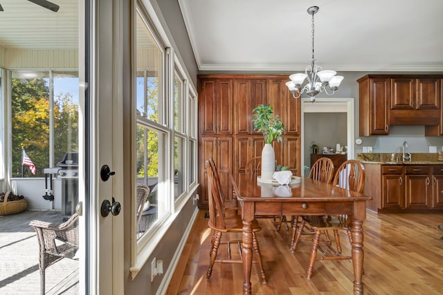 dining room with sink, crown molding, light hardwood / wood-style flooring, and ceiling fan with notable chandelier