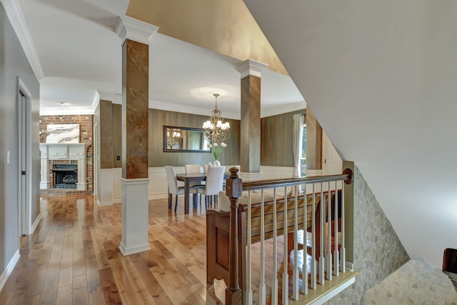 stairway featuring ornamental molding, an inviting chandelier, hardwood / wood-style floors, and a fireplace