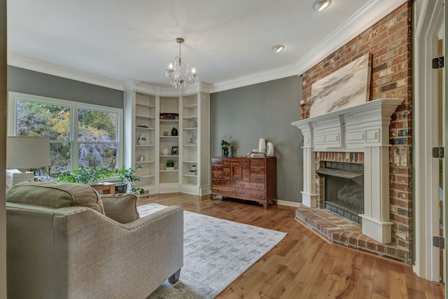 living area featuring crown molding, hardwood / wood-style floors, a notable chandelier, and a brick fireplace